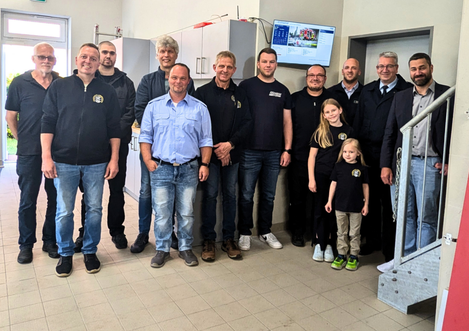 Gruppenbild: Vertreter der Ortsfeuerwehren, Förderverein, Spendengeber und Samtgemeindebürgermeister Christoph Busboom vor Alarmmonitor.
